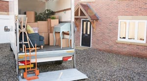 Removal Truck Waiting To Be Unloaded Outside New Home On Moving Day